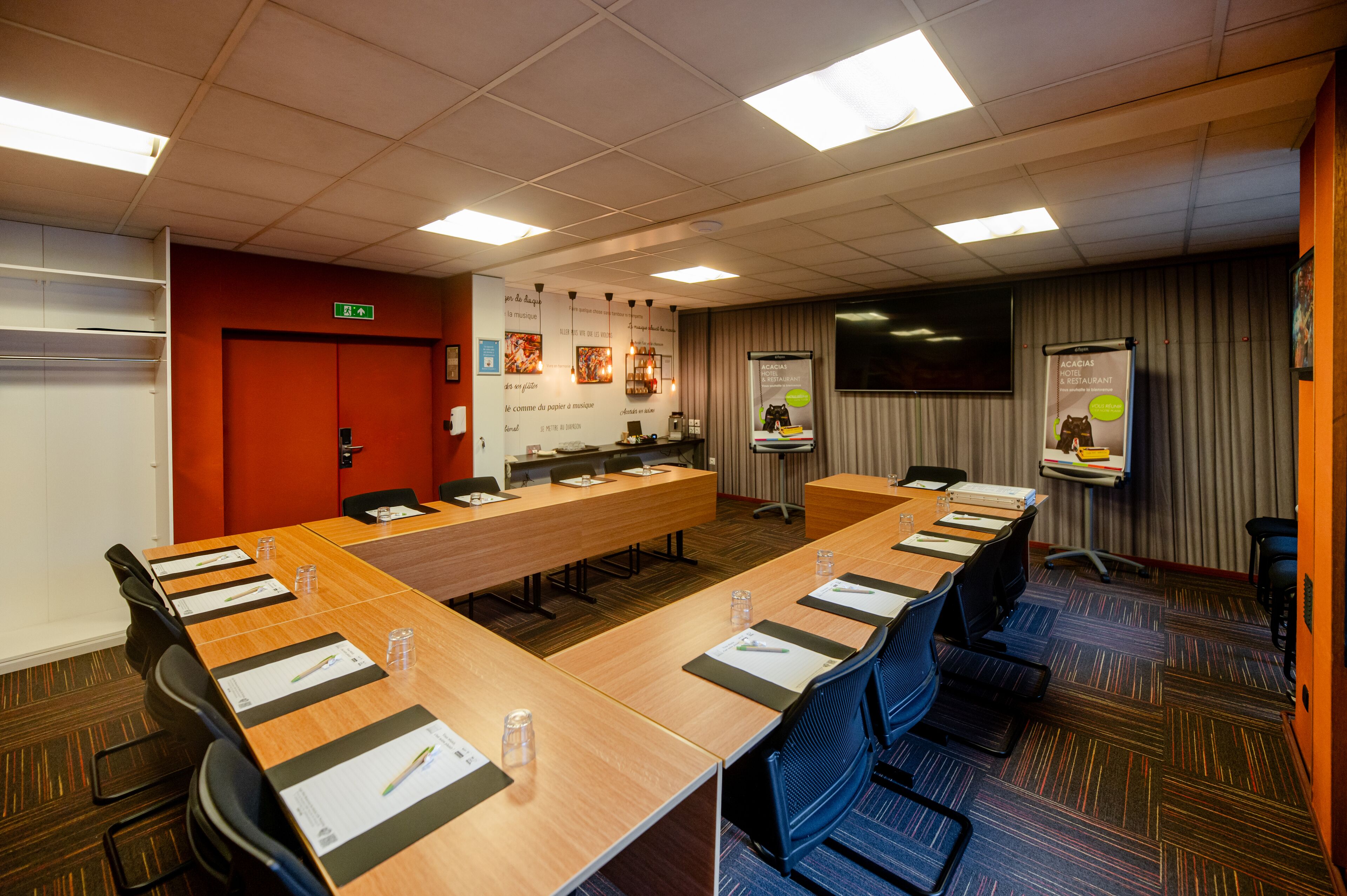 Ein Konferenzraum mit einem langen Tisch, Stühlen und einer Projektionsleinwand.