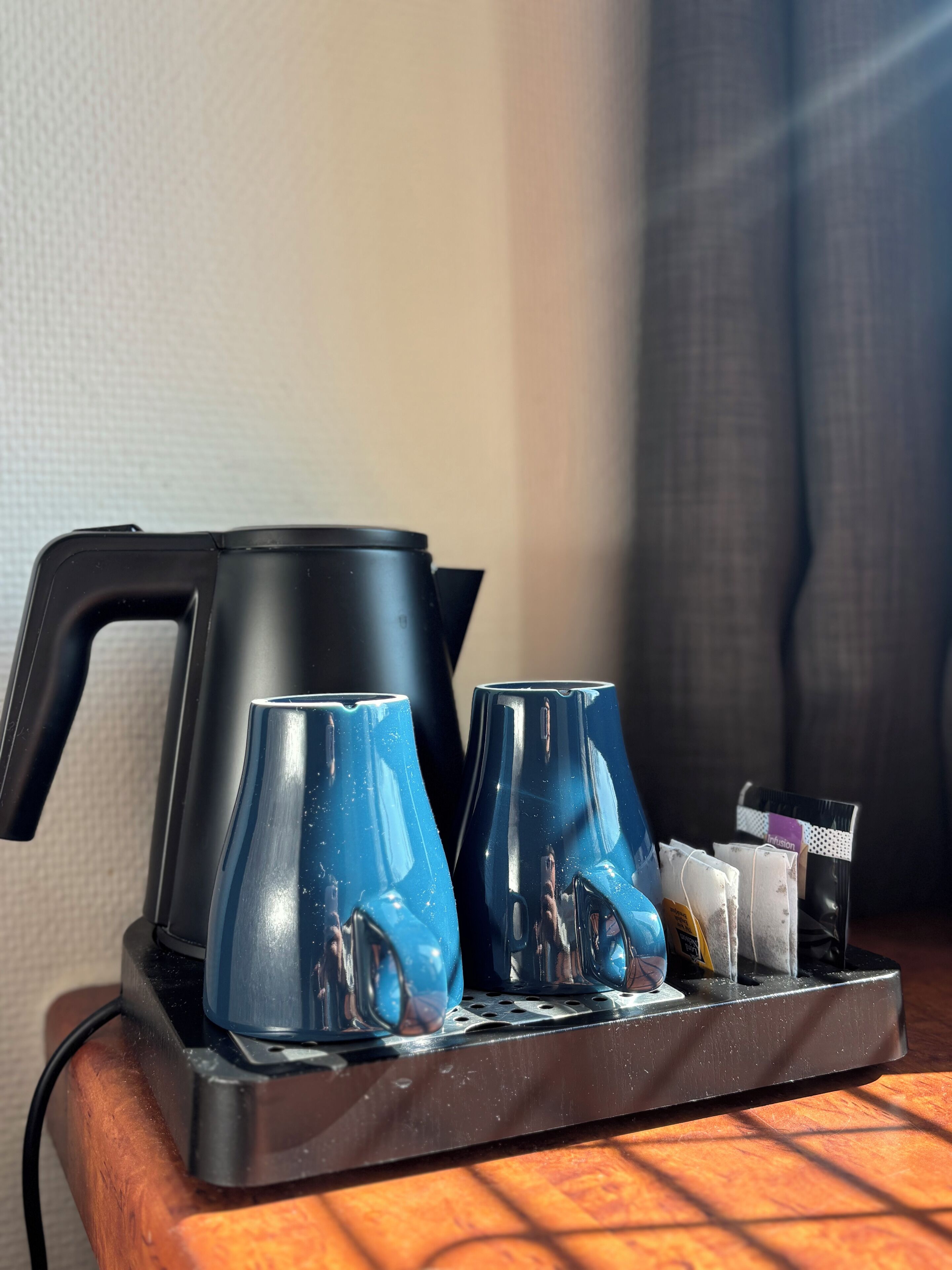Un coin café avec deux tasses bleues et une cafetière noire, le tout disposé sur un plateau.