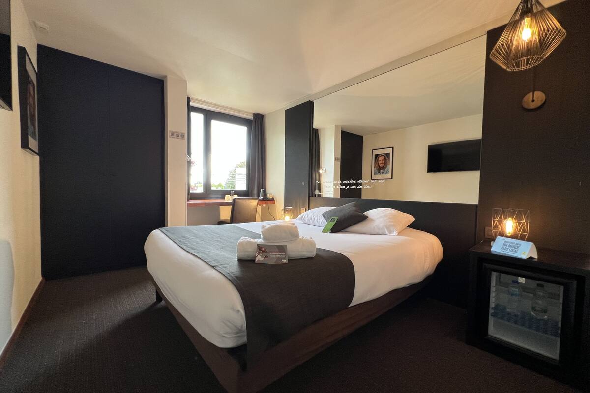 Een moderne hotelkamer met een groot bed, nachtkastje en een ingebouwde televisie.