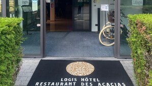 The entrance to Hotel Des Acacias with a modern glass facade, a black mat with the hotel's name, and a logo on the ground. - Logis Hotel Restaurant des Acacias Lille Tourcoing (Neuville-en-Ferrain)