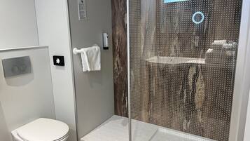 Un baño moderno con inodoro, ducha con puerta de cristal y un perchero para toallas.