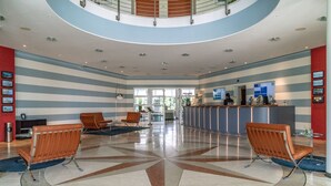 A spacious lobby with a central geometric tile design, a reception desk, and seating areas.