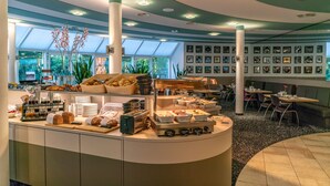 A modern breakfast area with a buffet setup, including bread, pastries, and various breakfast items.