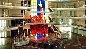 A multi-level atrium with a central glass sculpture, multiple staircases, and a polished marble floor.