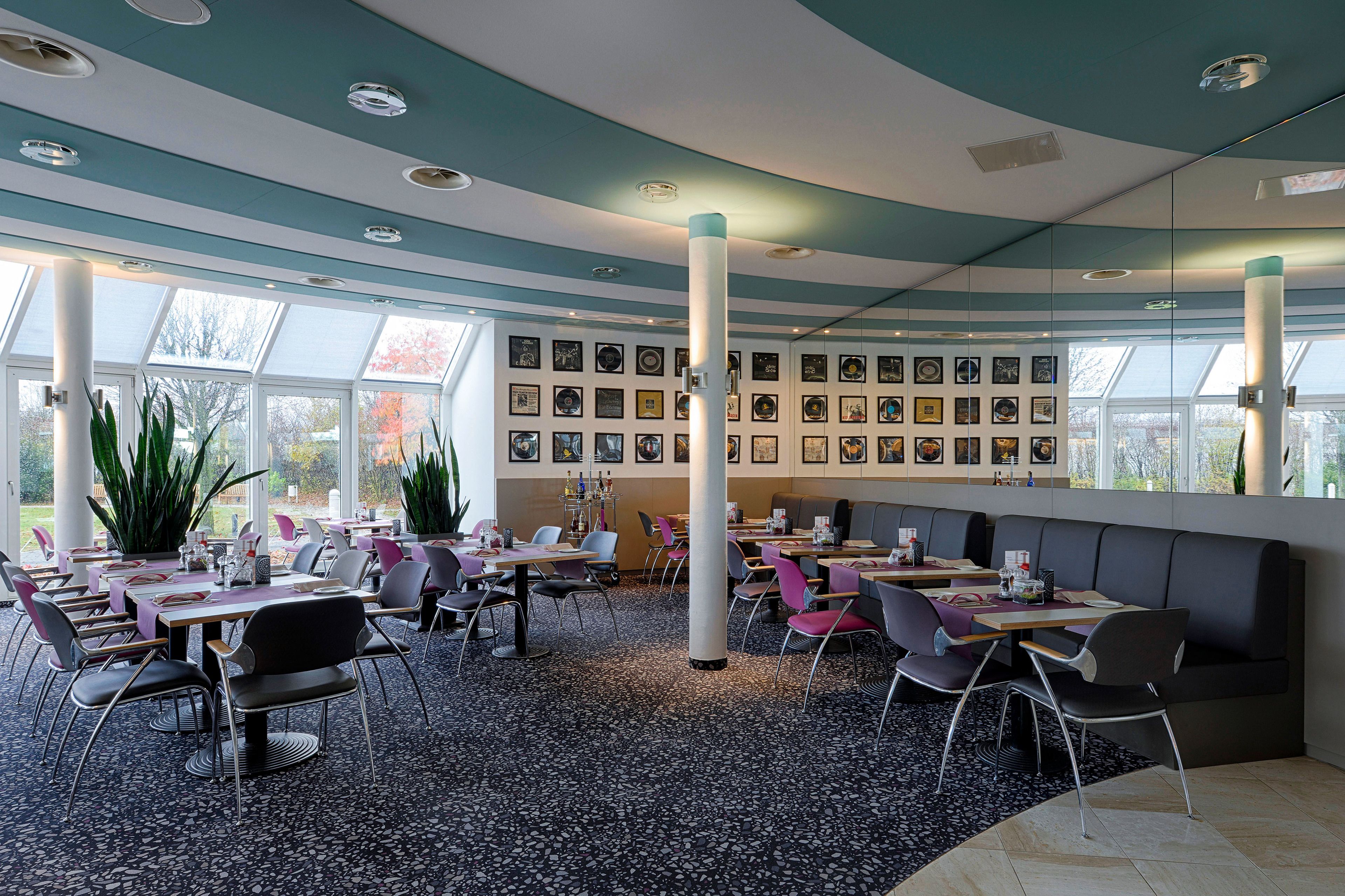A modern restaurant with round tables, chairs, and a wall of framed pictures.
