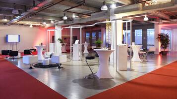 A modern conference room with white furniture, a red carpet, and a large screen on the wall.