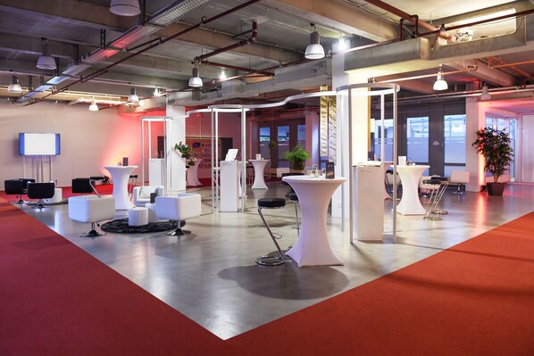 A modern conference room with white furniture, a red carpet, and a large screen on the wall.