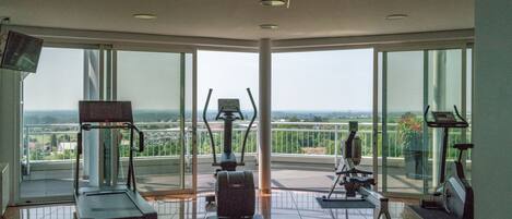A gym with exercise equipment and large windows offering a view of the city.