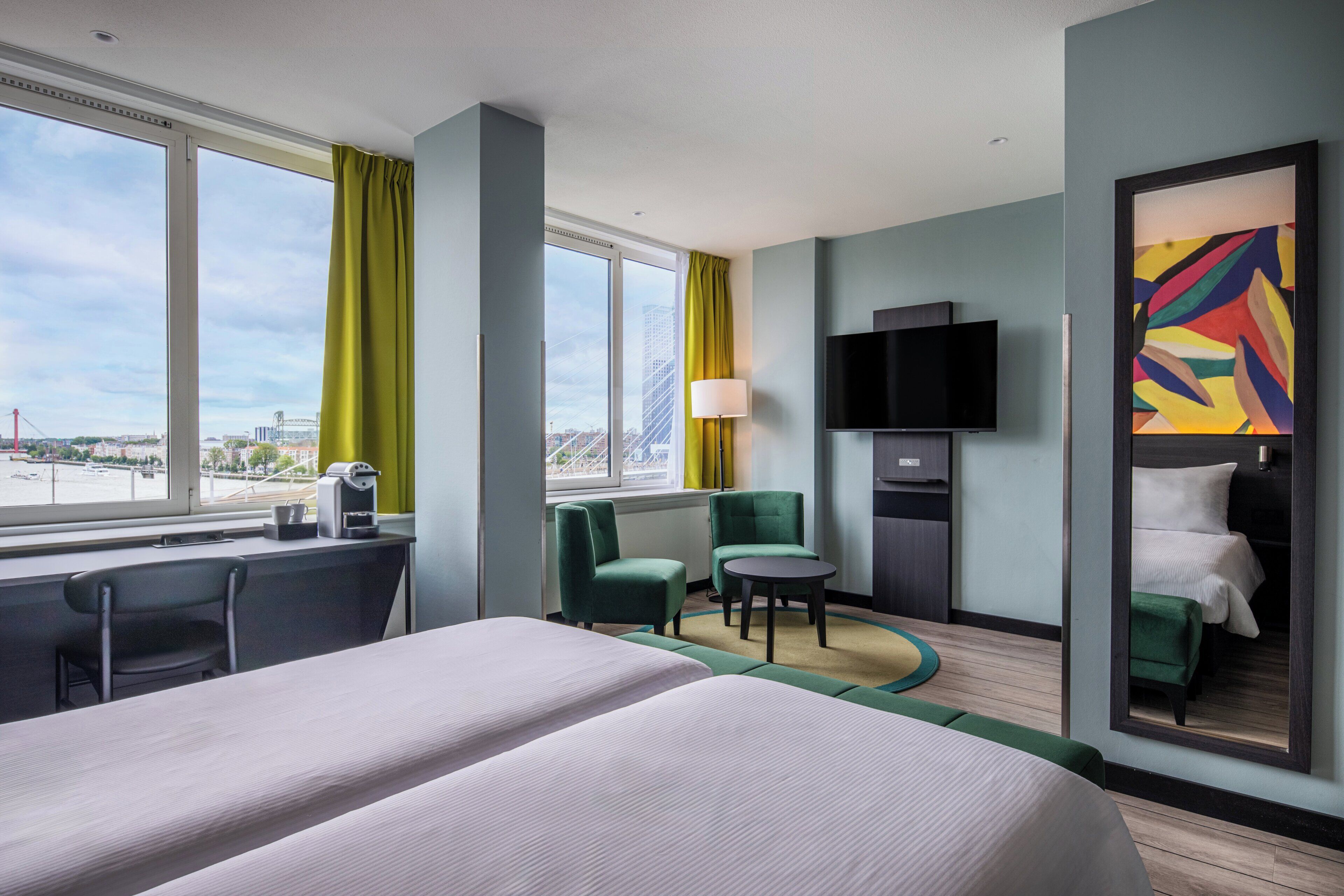 A hotel room with a bed, a desk, a chair, a TV, and a large window with curtains.