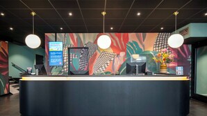 A reception desk with a digital screen, a telephone, and a vase with flowers. - Thon Hotel Rotterdam (Rotterdam)