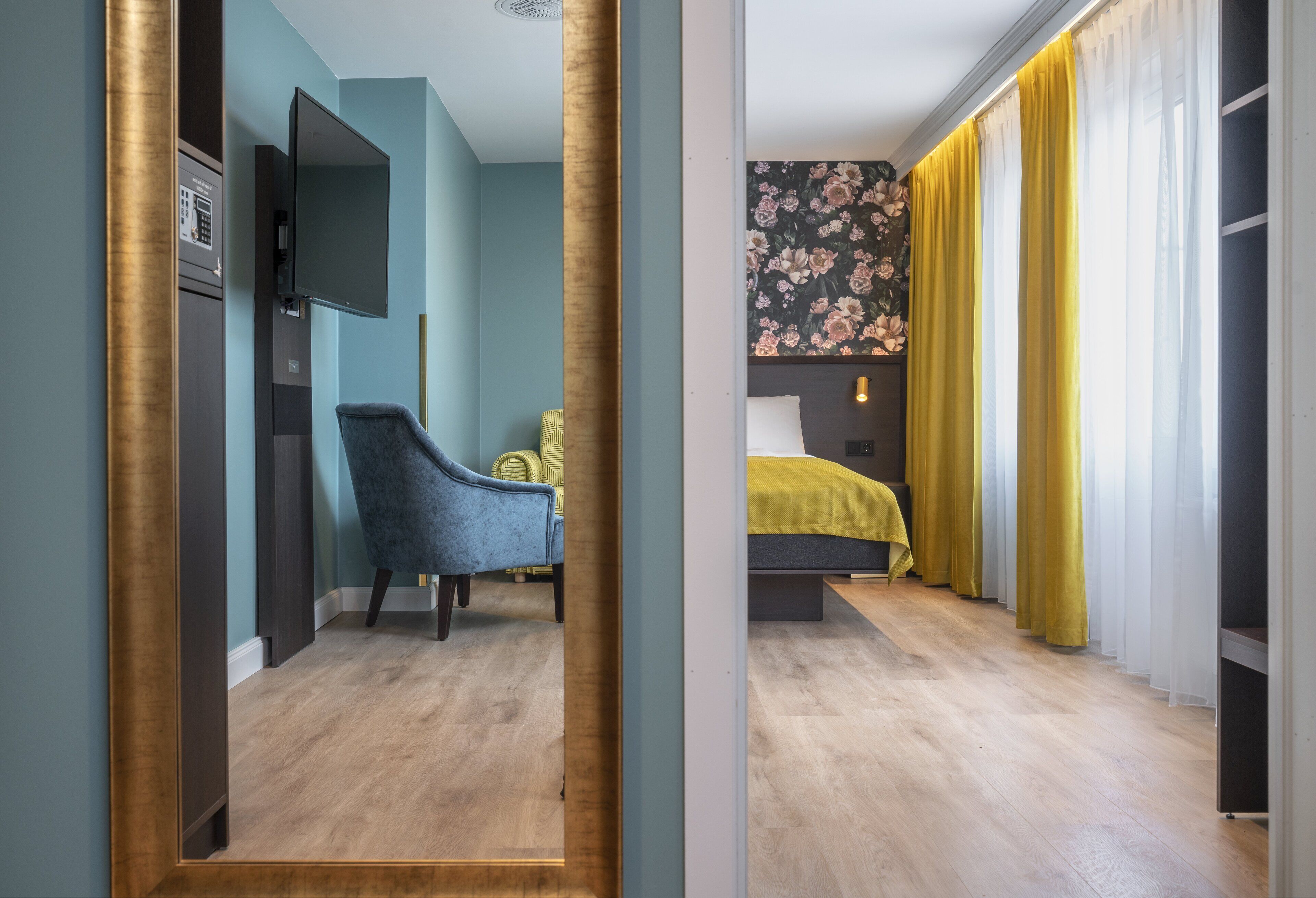 A hotel room with a bed, a chair, a television, and a wardrobe.