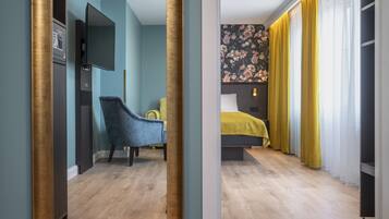 A hotel room with a bed, a chair, a television, and a wardrobe.