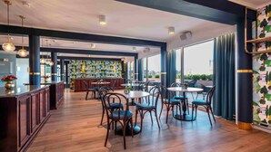 Un restaurant moderne avec un plancher en bois, des tables rondes et des chaises bleues.