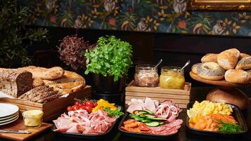 Una mesa de buffet con diversos alimentos, incluyendo pan, carnes, verduras y salsas.