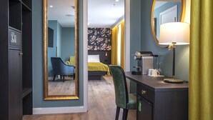 Une chambre d’hôtel avec un grand miroir, un bureau avec une lampe, une chaise et un lit recouvert d’une couverture jaune.