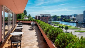 Un balcon avec coin salon extérieur, offrant une vue sur une rivière et le paysage urbain.