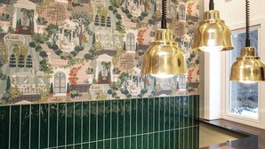 Une cuisine avec un mur recouvert de carreaux verts et une fresque décorative.