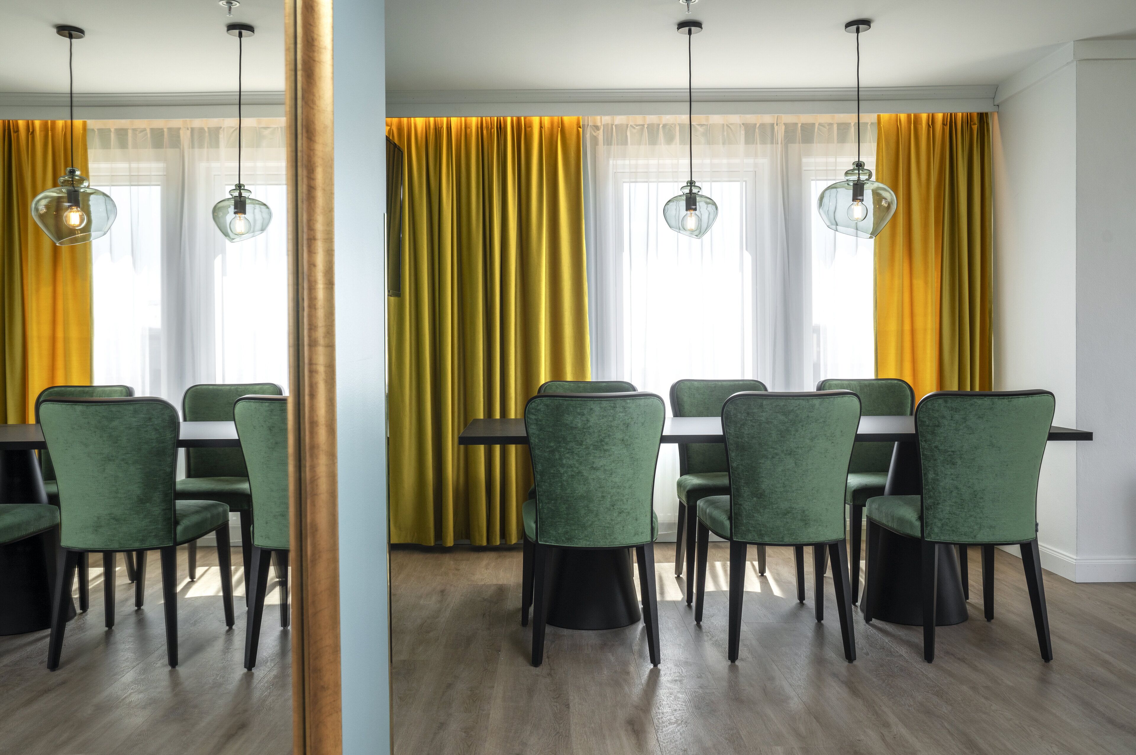 A dining area with a table and chairs, a window with yellow curtains, and pendant lights.