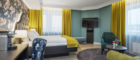 Une chambre d’hôtel avec un lit, un bureau, une chaise, une télévision et un canapé.
