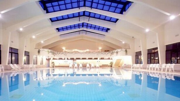 Piscina interior con vista despejada al techo, amplias ventanas y una zona de recepción.