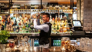 Un bar con una variedad de botellas de licor, vasos y una caja registradora.