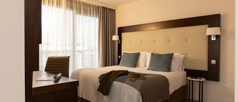 Una habitación de hotel con una cama grande, un escritorio y una silla.