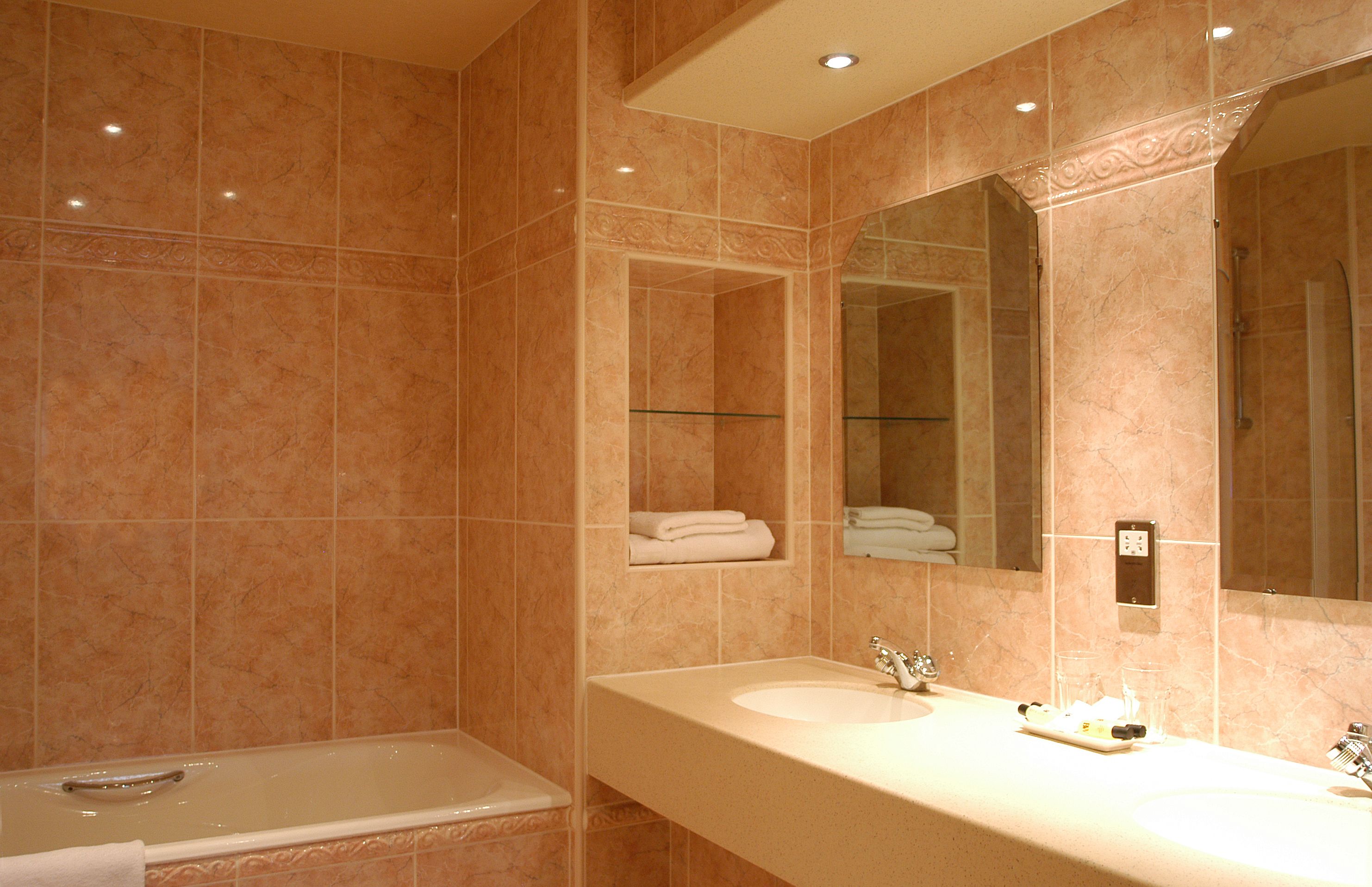 Ein Badezimmer mit einer Badewanne, einem großen Spiegel und einem Waschtisch.