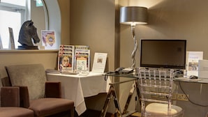 Ein Hotelzimmer mit Schreibtisch, Stuhl, Lampe und Fernseher.