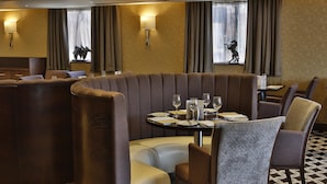 Ein Restaurant mit einer gebogenen Sitzecke, einem runden Tisch mit Stühlen und einem gemusterten Boden.