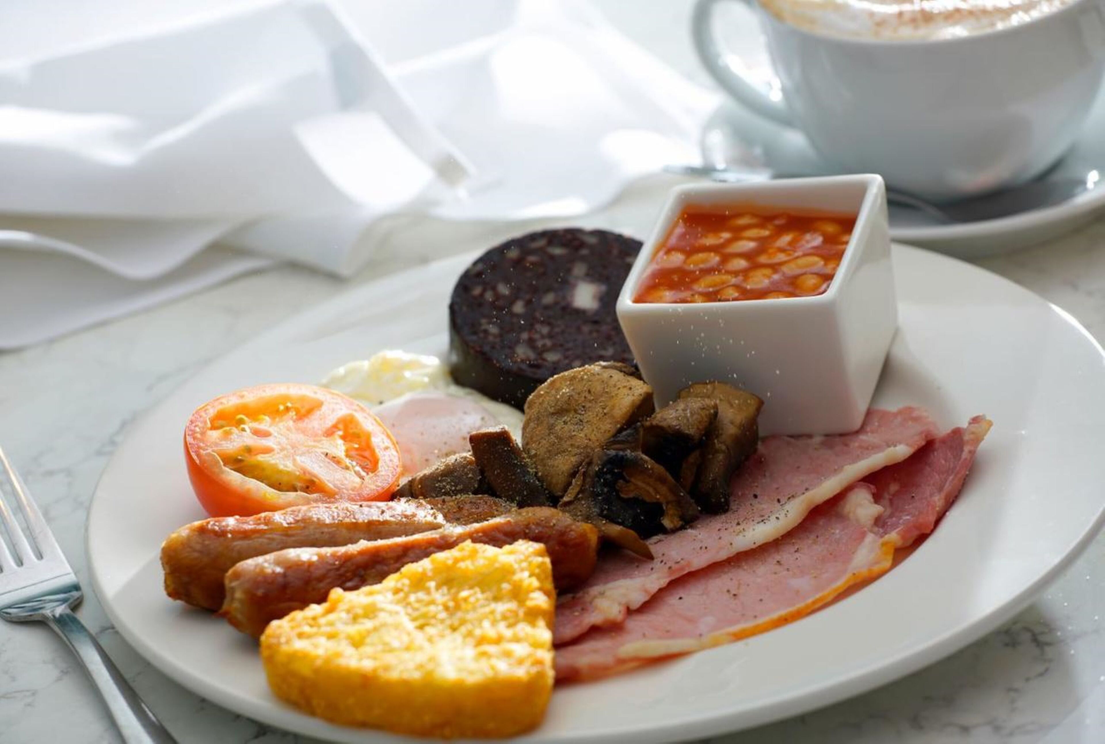 Une assiette de petit-déjeuner contenant divers aliments, notamment des œufs, du bacon, des saucisses et des haricots.