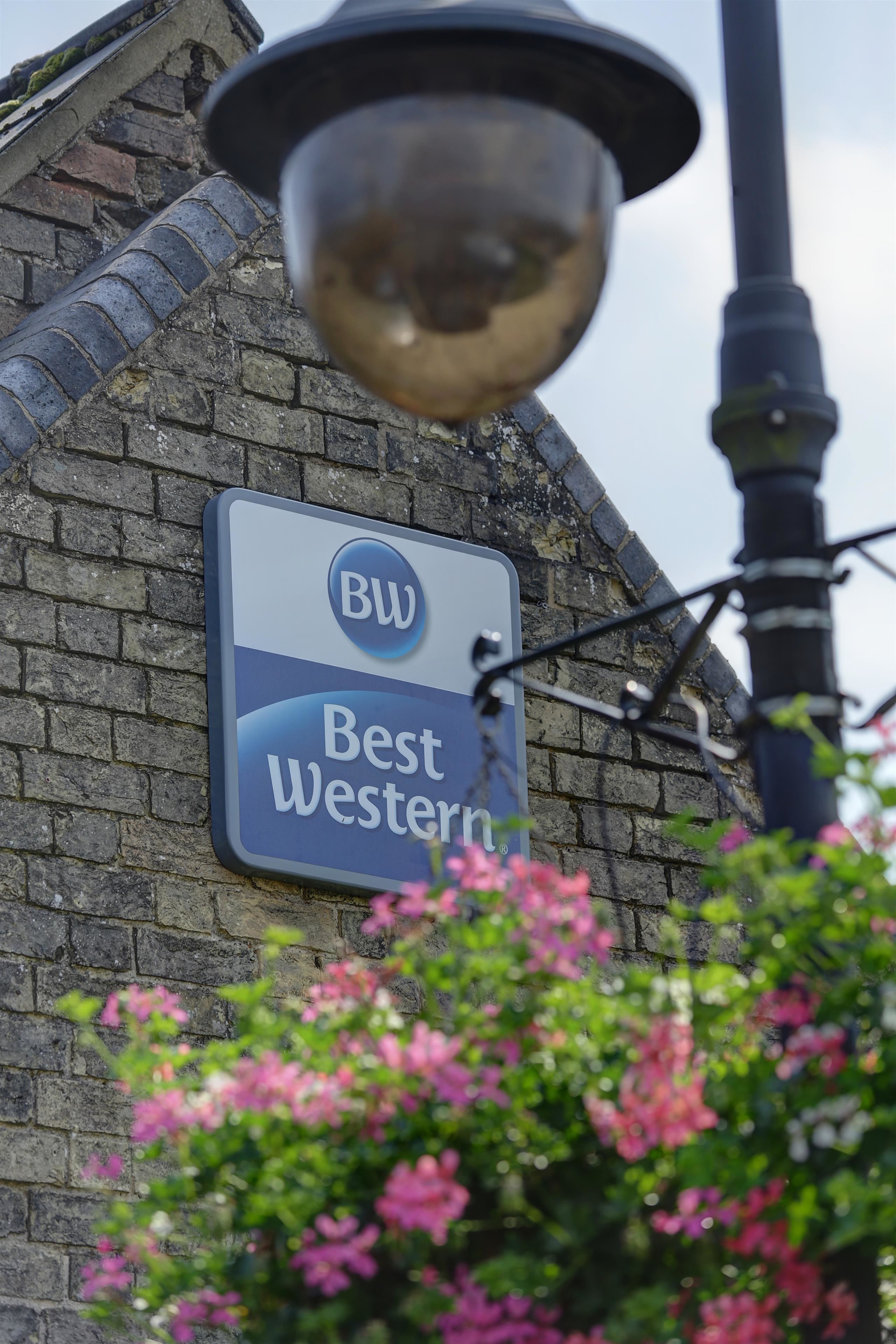 A sign for 'Best Western' hotel with a clear view of the brick building facade and a street lamp in the foreground.