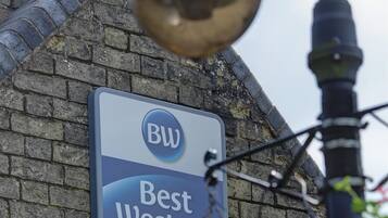 A sign for 'Best Western' hotel with a clear view of the brick building facade and a street lamp in the foreground.