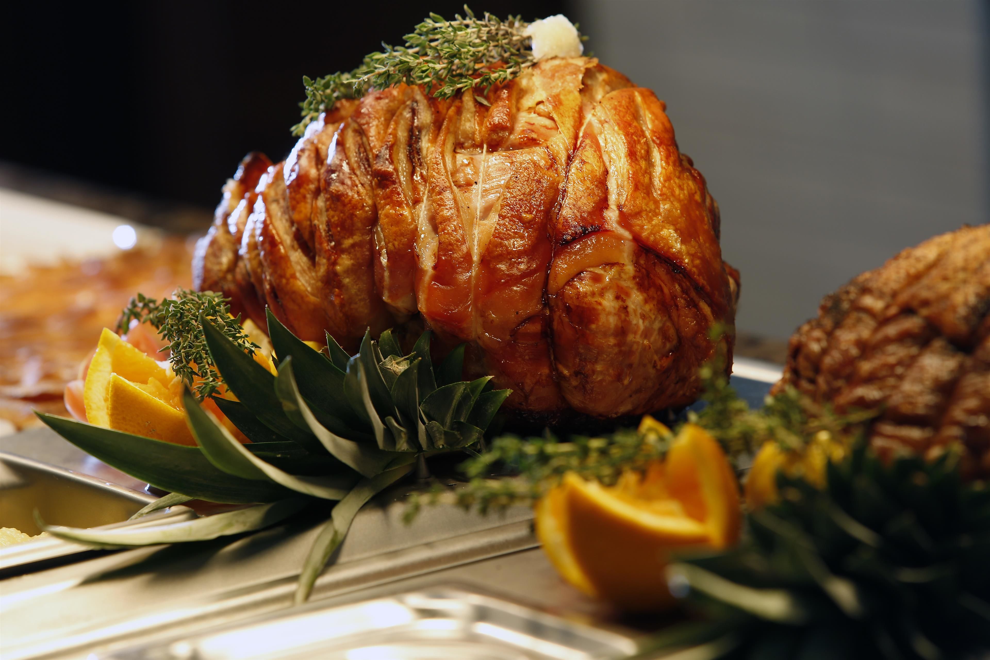 A roasted turkey garnished with herbs and orange slices on a serving platter.