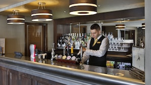 Eine Bar mit Bartender, einer gut sortierten Bar mit verschiedenen Flaschen und Gläsern sowie moderner Pendelleuchten.