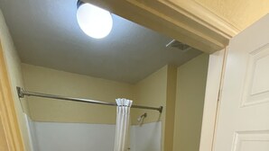 A bathroom with a bathtub, toilet, and a shower curtain. - Gun Barrel Executive Inn (Mabank)