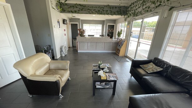 A modern reception area with a leather sofa, a black leather sofa, and a coffee table with magazines. - Gun Barrel Executive Inn (Mabank)