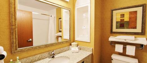 A bathroom with a granite sink, a large mirror, a toilet, and a towel rack.