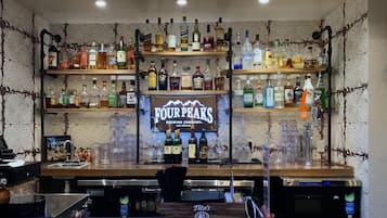 A bar area with multiple shelves stocked with various liquor bottles, a sign for 'FOUR PEAKS BREWING COMPANY, ARIZONA', and a counter with a 'STELLA ARTOIS' branded coaster.