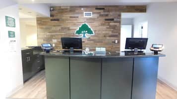 Una recepción con dos monitores, una pantalla digital y una caja registradora.