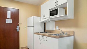 A compact kitchen with white cabinets, a built-in microwave, a refrigerator, and a sink. - Extended Stay America Select Suites Detroit Farmington Hills (Farmington Hills)