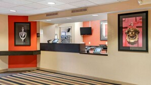 A hotel reception area with a reception desk, a large mirror, and a framed artwork on the wall. - Extended Stay America Select Suites Detroit Farmington Hills (Farmington Hills)