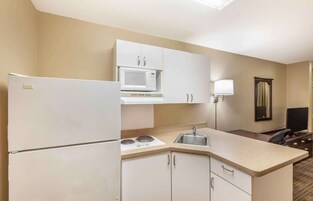 Una cocina compacta equipada con refrigerador, microondas, estufa y pileta.