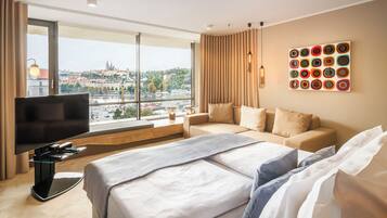 Quarto de hotel com uma janela grande, uma cama, uma televisão e uma obra de arte na parede.