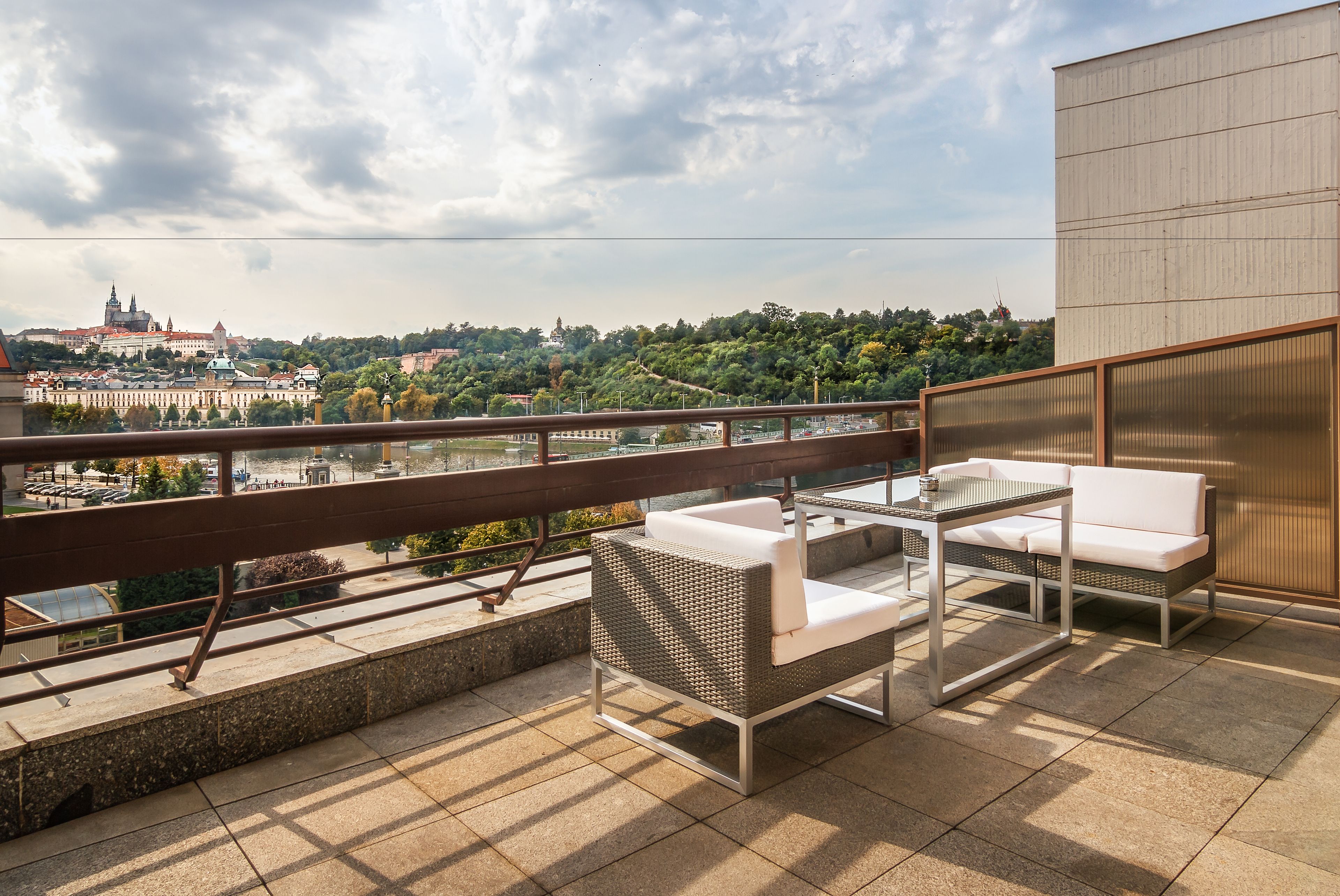 Een balkon met buitenmeubilair en uitzicht op een stadsgezicht en een rivier.