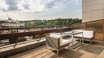 Een balkon met buitenmeubilair en uitzicht op een stadsgezicht en een rivier.