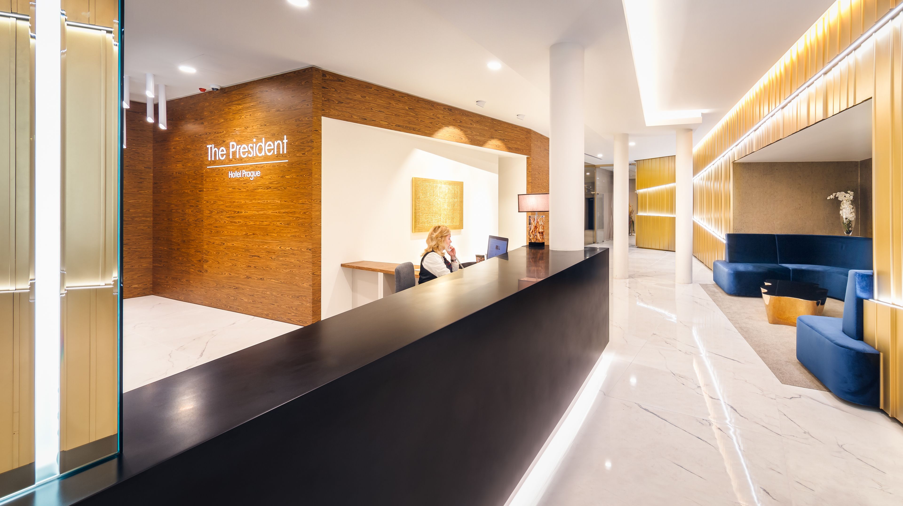 A reception area with a wooden accent wall, a black reception desk, and blue seating.