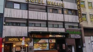 Un immeuble hôtelier à plusieurs étages, sur la façade duquel le nom « Hôtel Wallis » est clairement affiché.