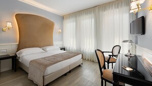 A hotel room with a large bed, bedside lamps, a desk with a chair, and a TV mounted on the wall. - Hotel San Luca (Verona)
