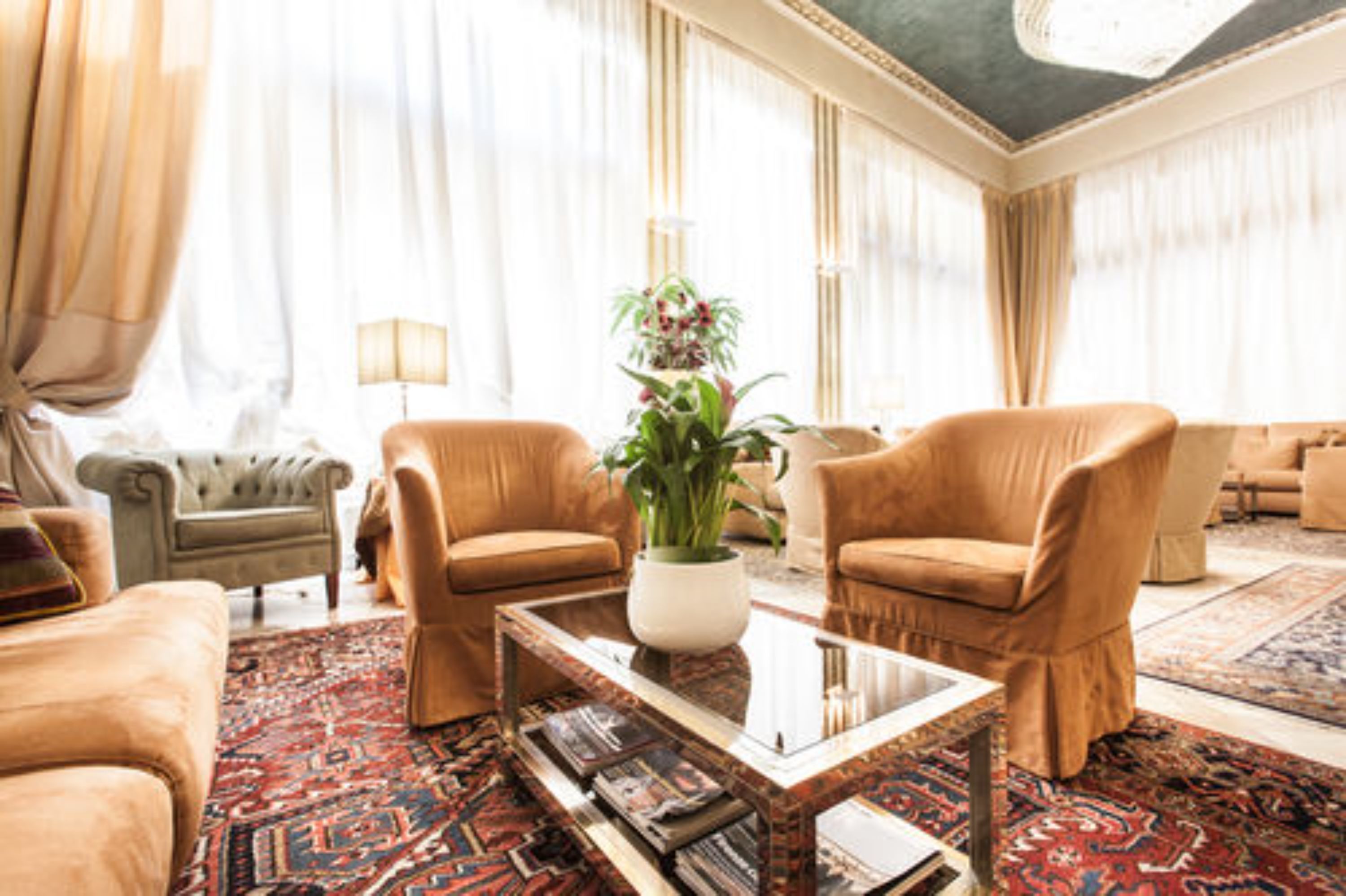 A spacious living room with a large window, a sofa, a coffee table, and a patterned rug.