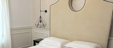 Una cama bien hecha con un cabecero color beige, una manta marrón y ropa de cama blanca.